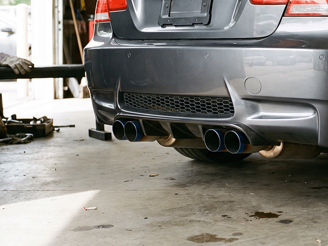 Close-up detail of a modified performance car's rear, aftermarket exhaust and lowered stance