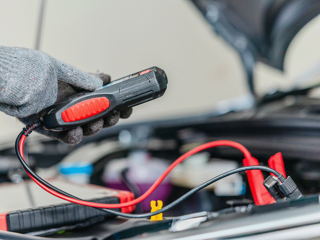 Mechanic using a diagnostic tool connected to a car's engine to identify a fault